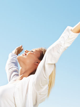 Woman with arms outstretched looking up at the sun, symbolising emotional freedom, personal growth, and letting go.