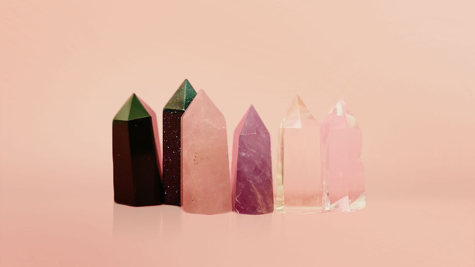 Crystal candles. Six colourful crystals in various shades stand against a soft pink background, displaying a serene and elegant arrangement.