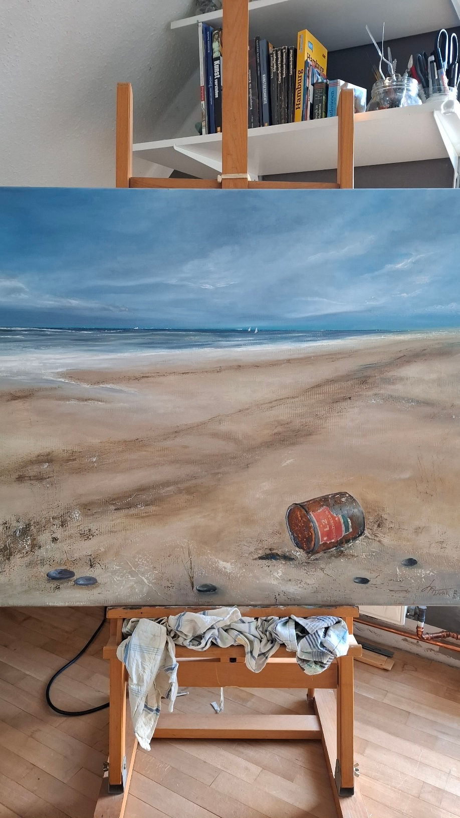 Painting of a rusty tin on the beach with the sea and small sailboats in the distance.