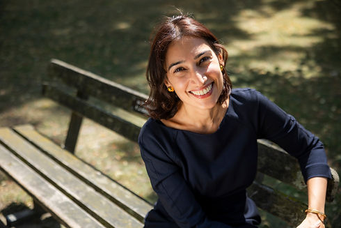 Pooja Sachdev smiling outdoors, leaning against a wooden railing