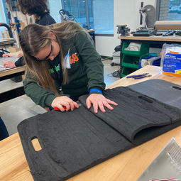 team member from The Ones Who shall not be named cutting a piece of foam