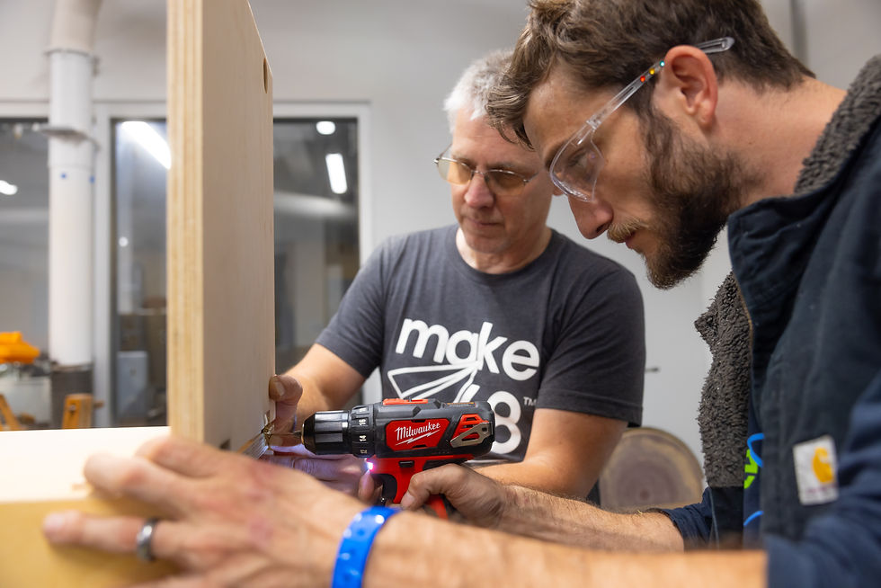two tool techs working together drilling a screw into wood