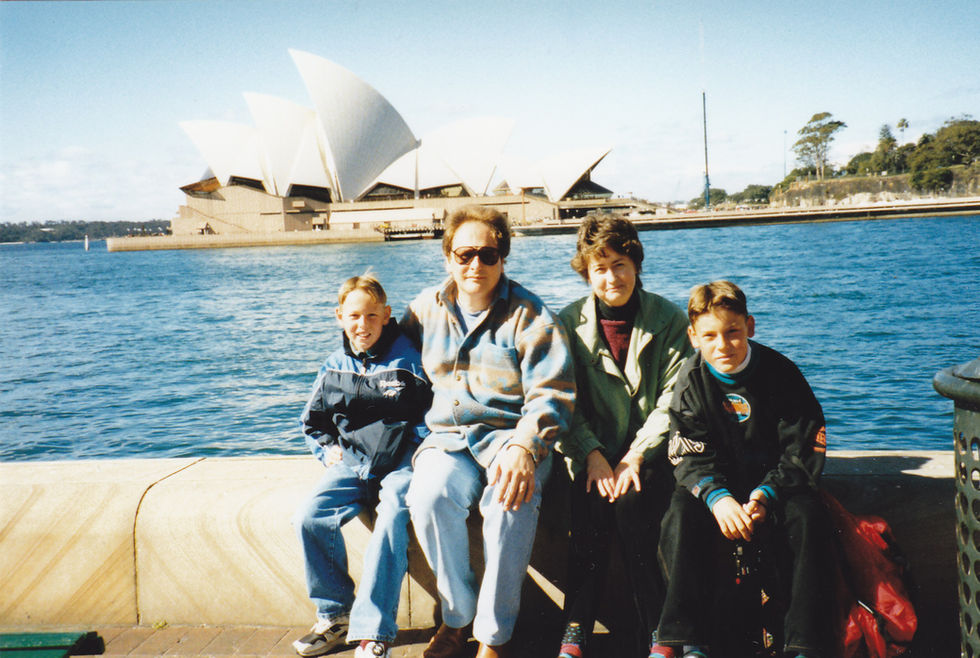 Four people sitting by water, Sydney Opera House background.