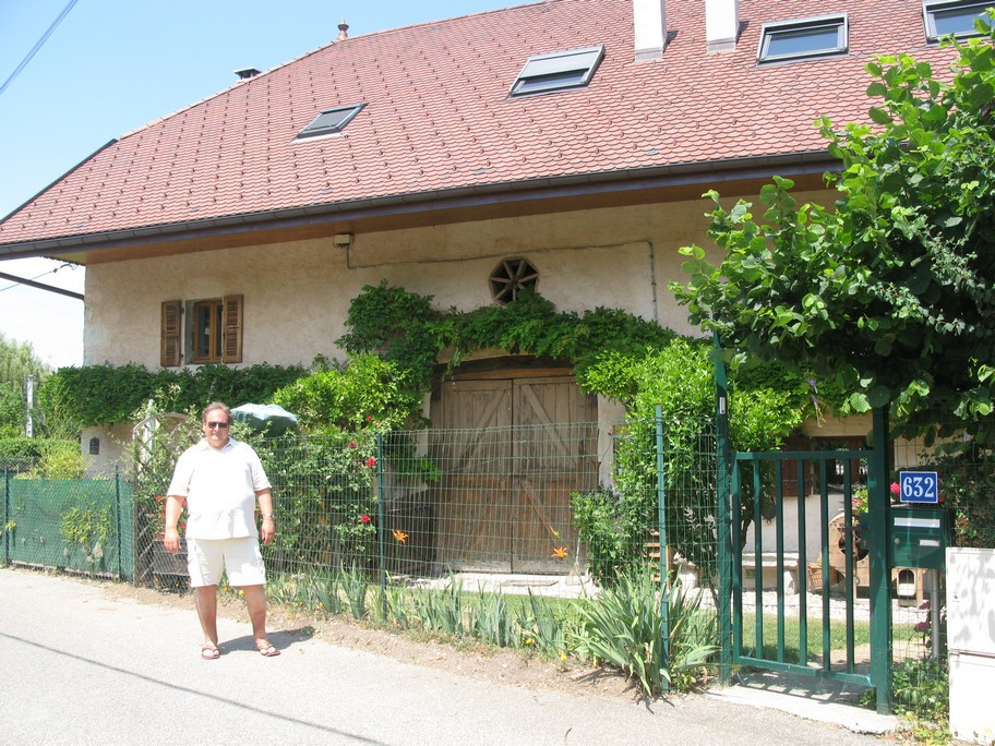 Man standing in front of a house with greenery.
