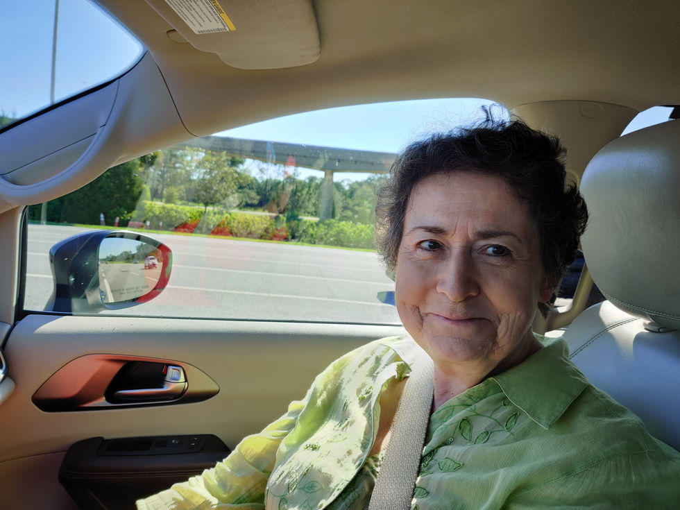A person sitting in a car, smiling.