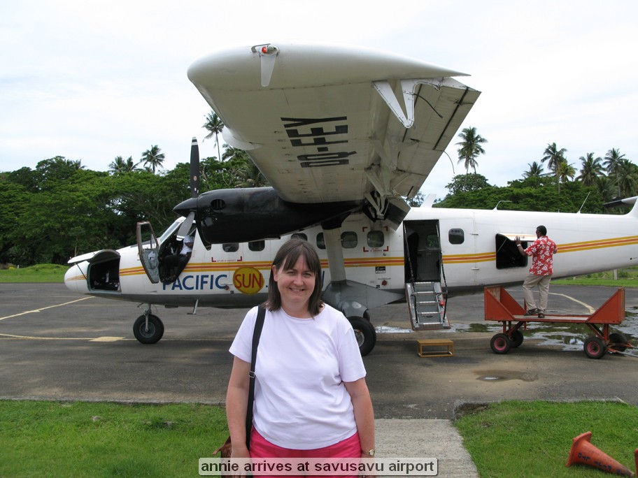 Woman standing in front of small airplane at airport.