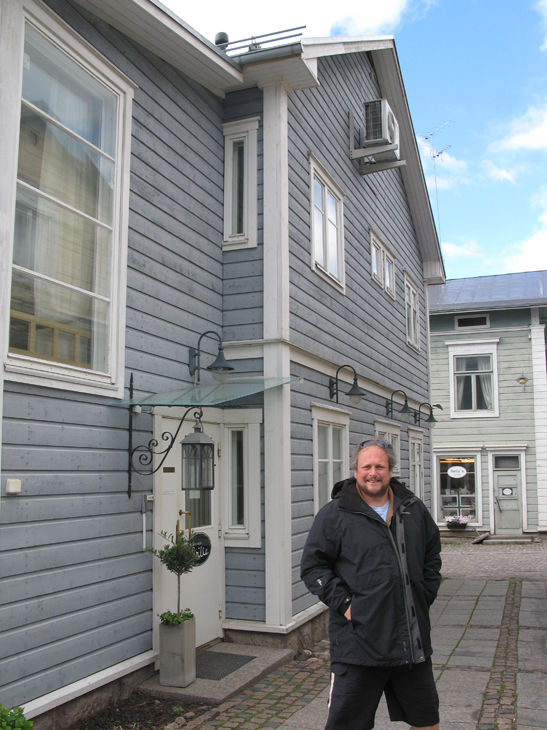 Man standing in front of gray wooden building.