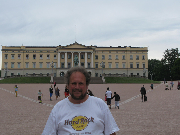 Man in Hard Rock Cafe shirt near a large building.