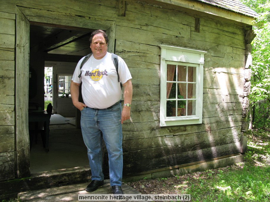 Man standing outside rustic wooden building.