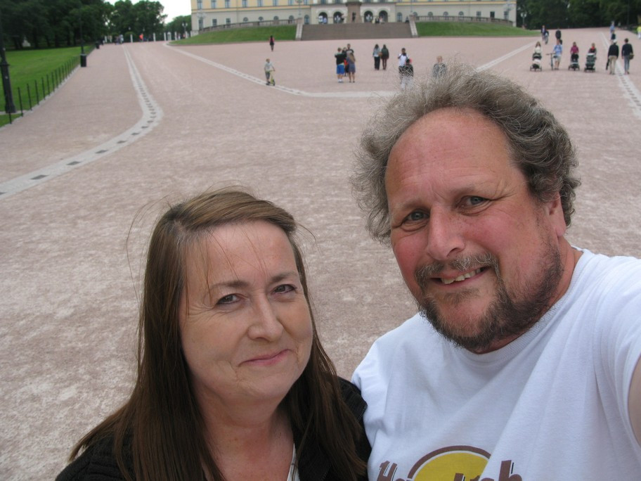 A couple smiling in front of a large building.