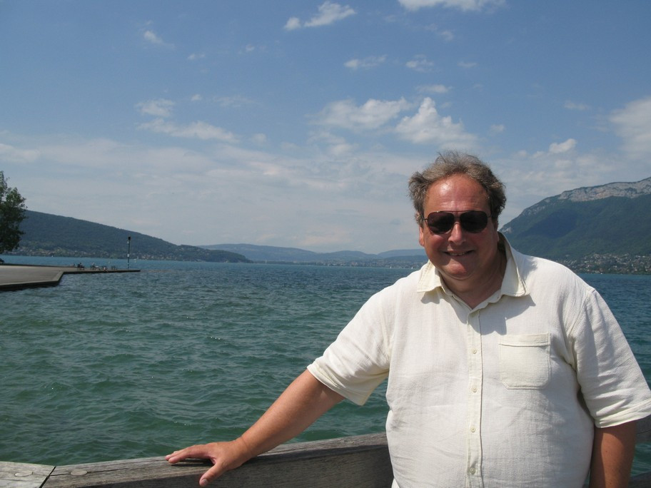 Man in sunglasses by a scenic waterfront.