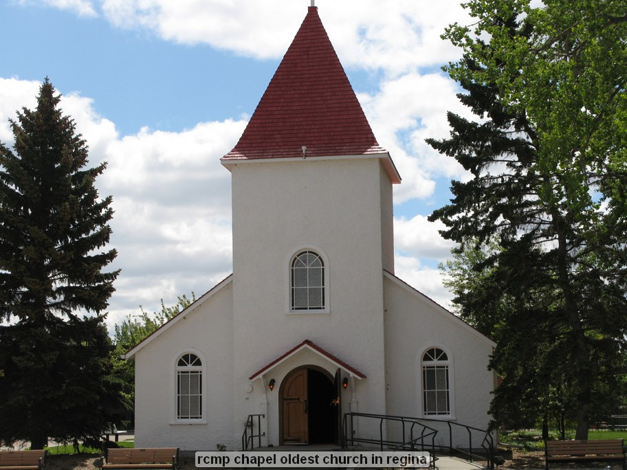 White chapel with red roof, surrounded by trees.