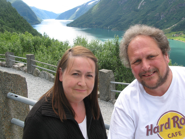 A couple posing with scenic mountain lake background.