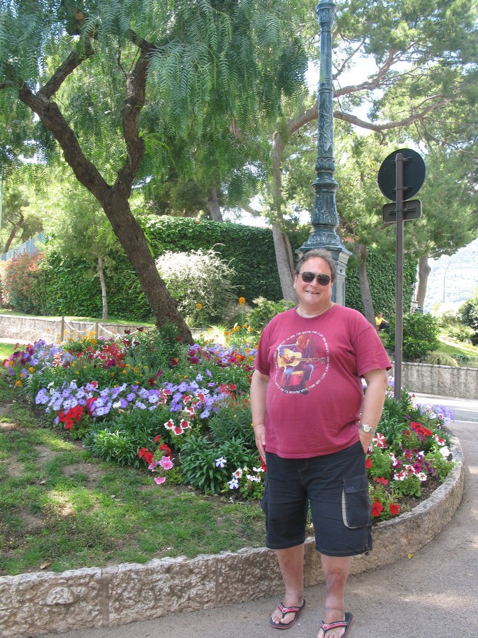 Person standing in a garden with colorful flowers.
