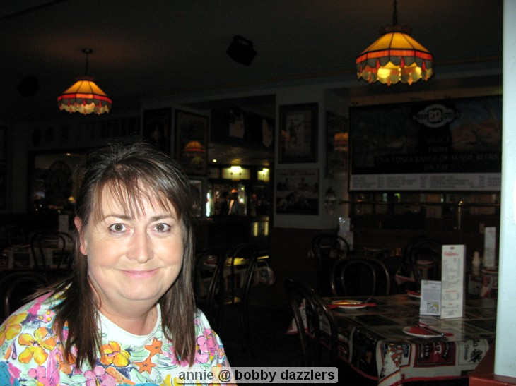 Woman smiling in a dimly lit restaurant.