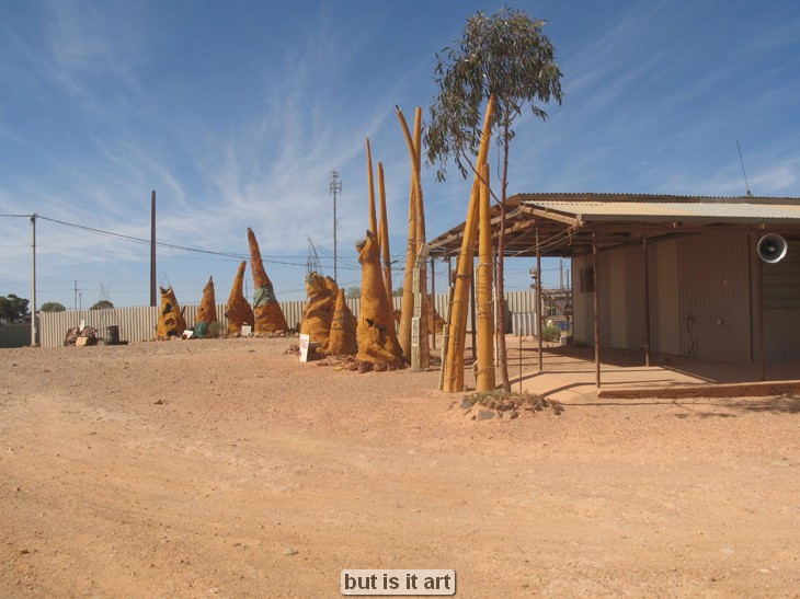 Outdoor installation with tall, abstract wooden sculptures.