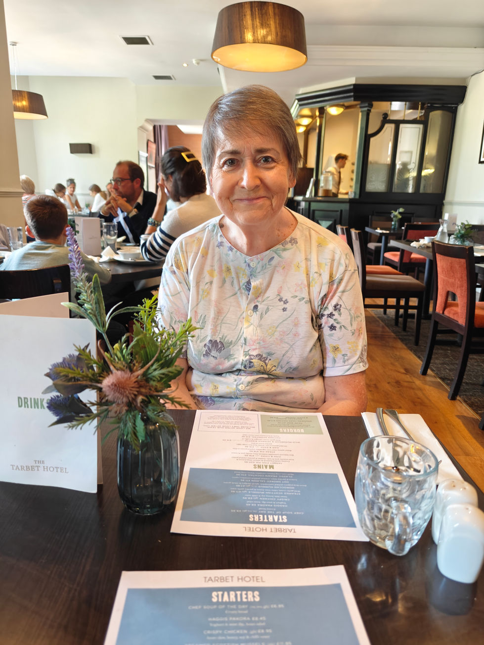 Elderly woman sitting at a restaurant table.