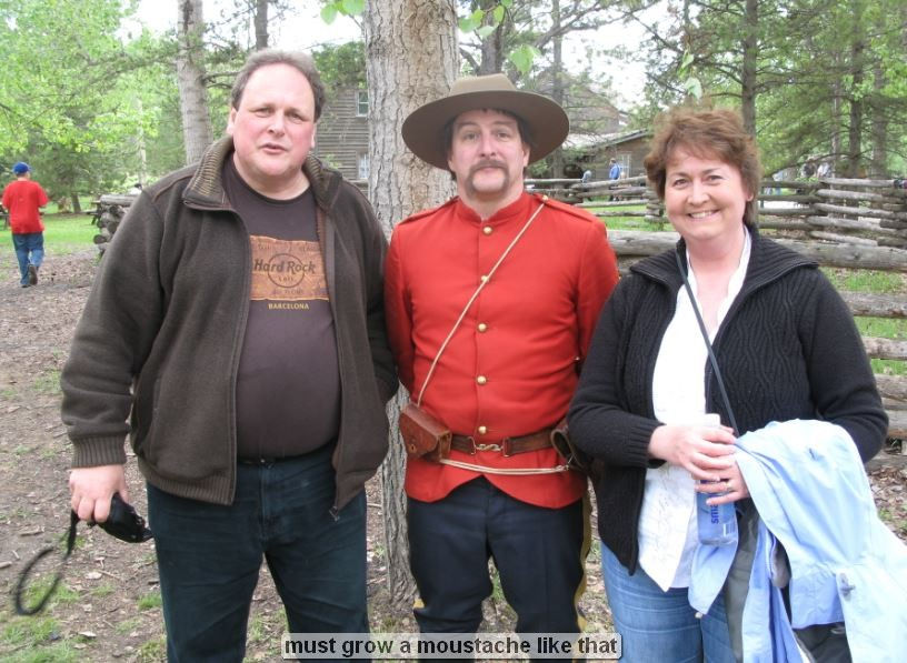 Three people posing outdoors, one in a red uniform.