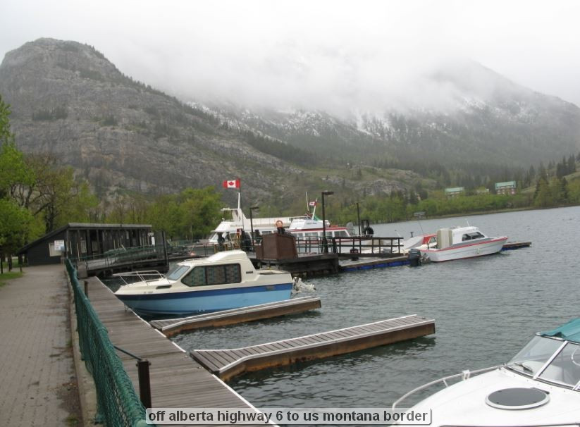 Boats docked on a misty lake with mountains.