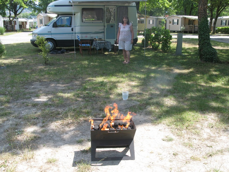 Person near camper van with outdoor fire pit.