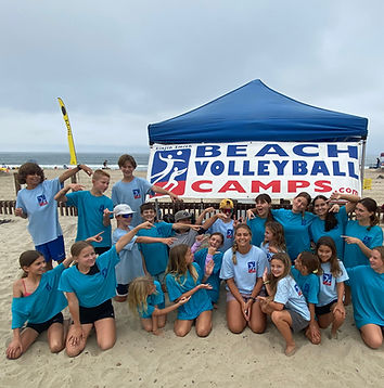 Youth and teen campers taking a photo with one coach during summer beach volleyball camp in Encinitas at Moonlight Beach