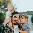 man in white shirt carrying girl in gray