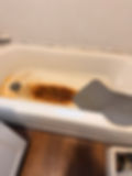 Stained bathtub with a grey non-slip mat.