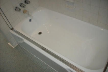 Clean white bathtub with chrome fixtures and tiled wall.