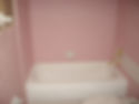 White bathtub surrounded by pink square wall tiles.
