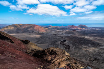 A captivating landscape photograph of Las Montanas del Fuego in Lanzarote, part of the dramatic volcanic scenery of the Parque Nacional de Timanfaya. This striking terrain reveals a raw, deserted beauty, with sweeping forms and a rich spectrum of ochre tones that define its unique character.