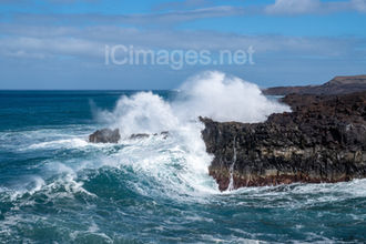 This striking photograph captures the raw power of the Atlantic as huge ocean swells crash against the volcanic cliffs of Los Hervideros, Lanzarote. Cascading back down the rugged black rocks under a brilliant blue sky, the waves reveal the dramatic energy and untamed beauty of the island’s coastline.