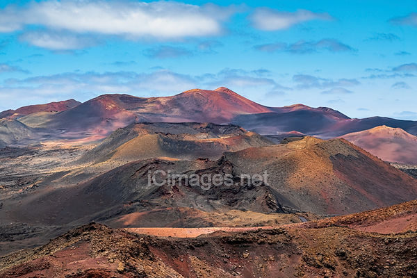 A landscape photograph of Las Montañas del Fuego in Lanzarote. A volcanic landscape like a walk on the Moon but on earth. They originated after the violent volcanic eruptions in the south of Lanzarote between 1730 and 1736 resulting in the Parque Nacional de Timanfaya. Las Montañas del Fuego have a deserted beauty, and a range of ochre shades that astound visitors.