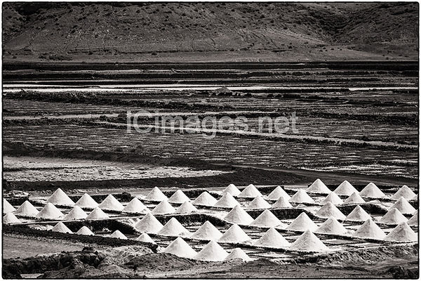 The salt reclamation area called Salinas de Janubio in Lanzarote. You can see the pyramids of salt that are to be been harvested.

A black and white image.