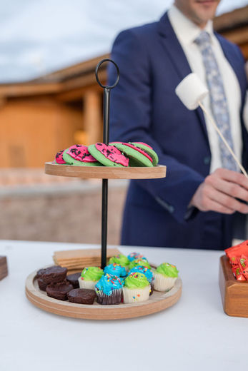 Tiered dessert tray with macarons, cupcakes, and marshmallows; party setting