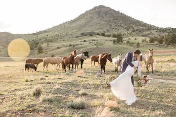 Couple kissing, horses grazing, mountain backdrop, The Copper Lodge wedding celebration