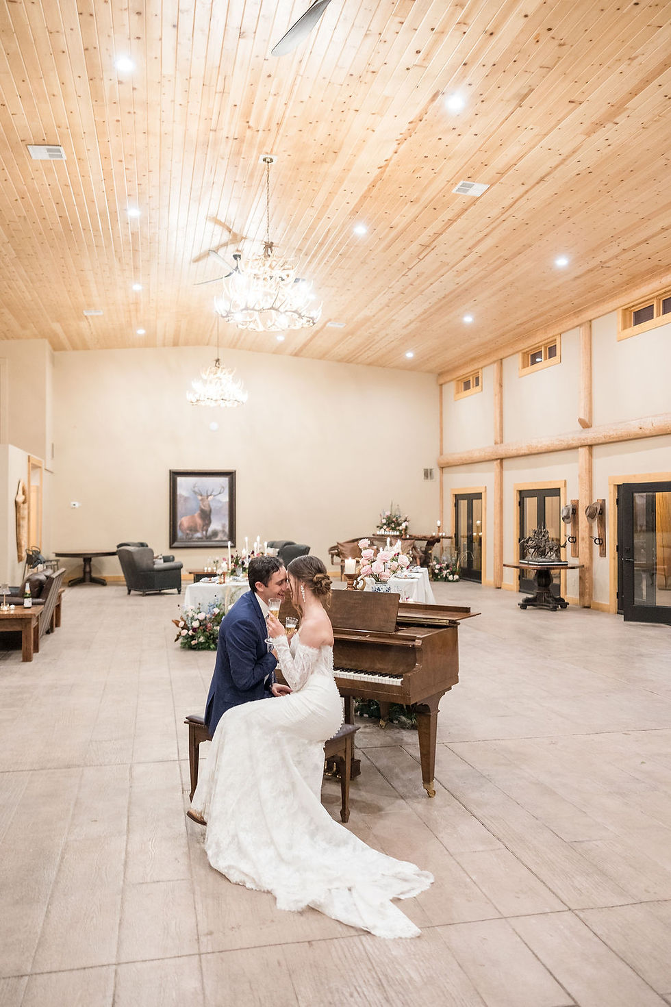 Bride and groom kissing, wedding dress, piano inside the venue at The Copper Lodge