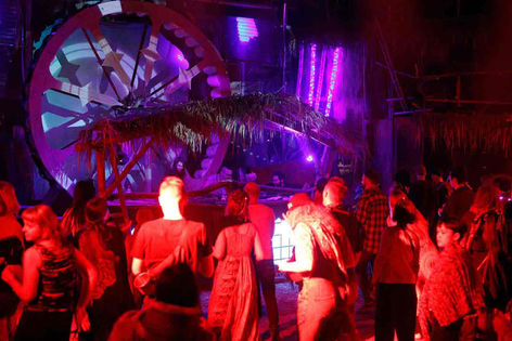 a group of people are standing in a dark room with purple lights .