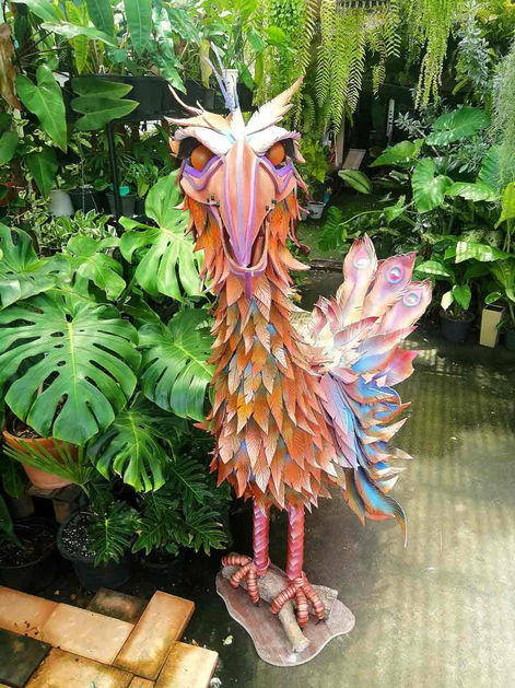 a statue of a bird with feathers on its wings is surrounded by potted plants