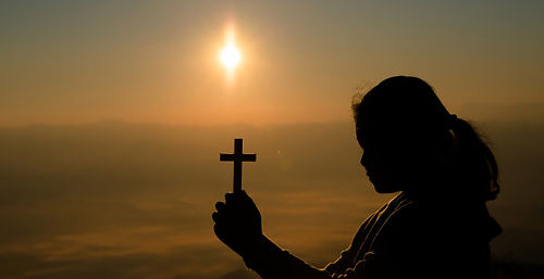 teenage-girl-holding-cross-with-praying-