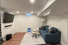 Finished basement living space in Oakville with modern flooring, recessed lighting and clean open layout