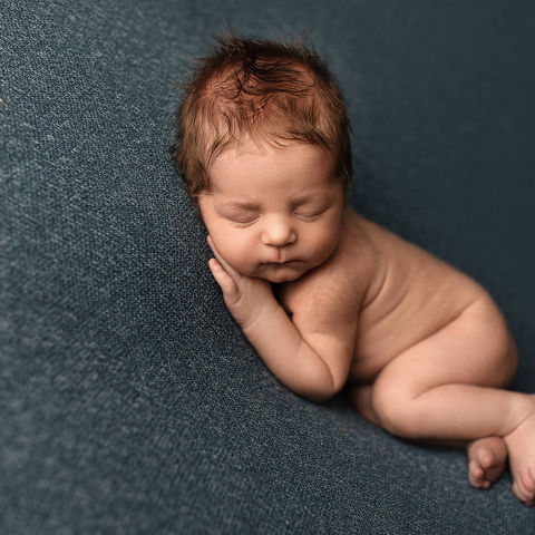 Cozy newborn baby posed on teal fabric during a Alpine, UT newborn photography session.