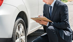 車の横でかがんで査定している男性