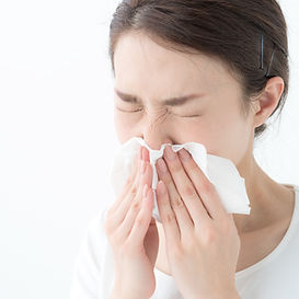 ティッシュで鼻をかむ女性