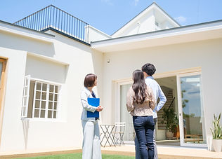 家を案内する不動産業者から説明をきく夫婦
