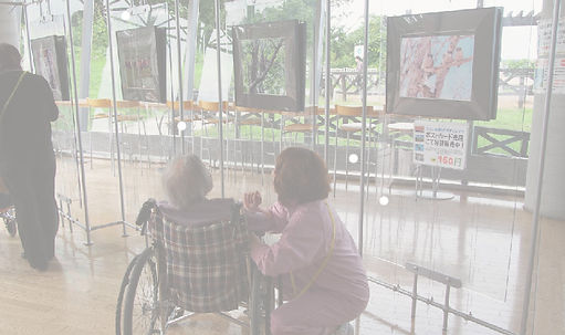 館内で車いすの高齢者に寄り添うセラピーこざくらのスタッフ