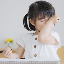 かゆい目元に手をあてる女の子