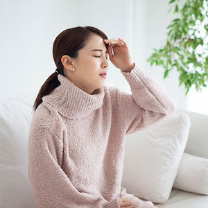 額に手をあてる具合の悪そうな女性