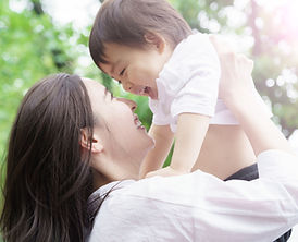 笑う子供を抱き上げる笑顔の母親