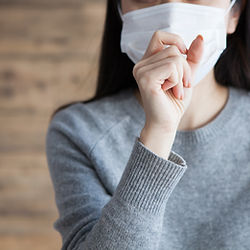 口元に手をあてるマスク姿の女性