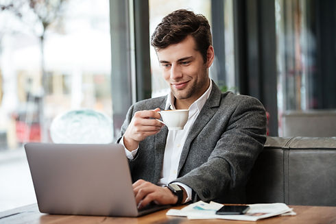 empresario-sorridente-sentado-junto-a-mesa-no-cafe-e-usando-o-computador-portatil.jpg